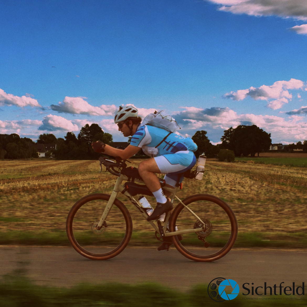 Silas von der Heyden seitlich auf dem Fahrrad unter blauem Himmel